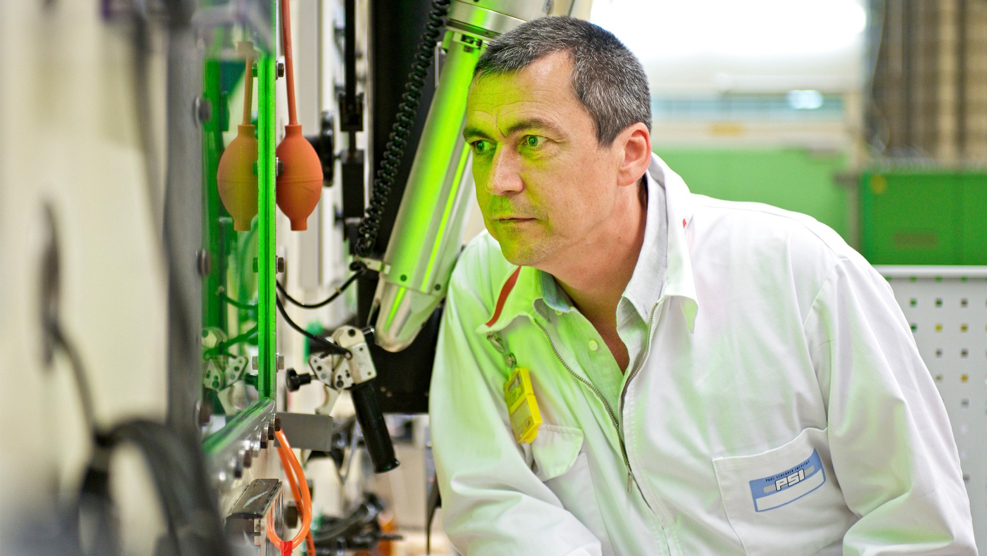 A man looking into the cell, with green light glowing from inside the cell.